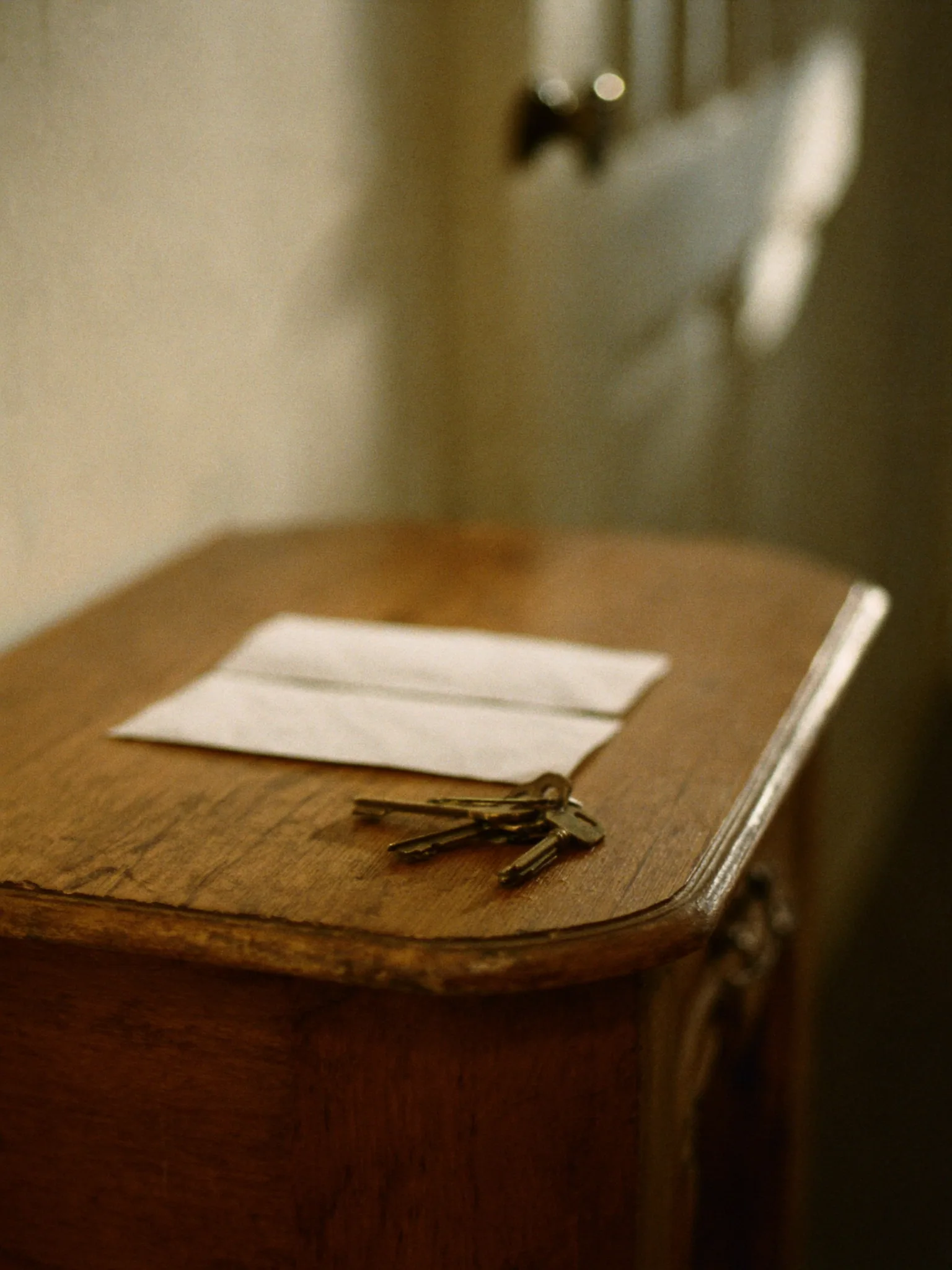 Brass keys on a hallway table beside unopened envelopes, soft afternoon light