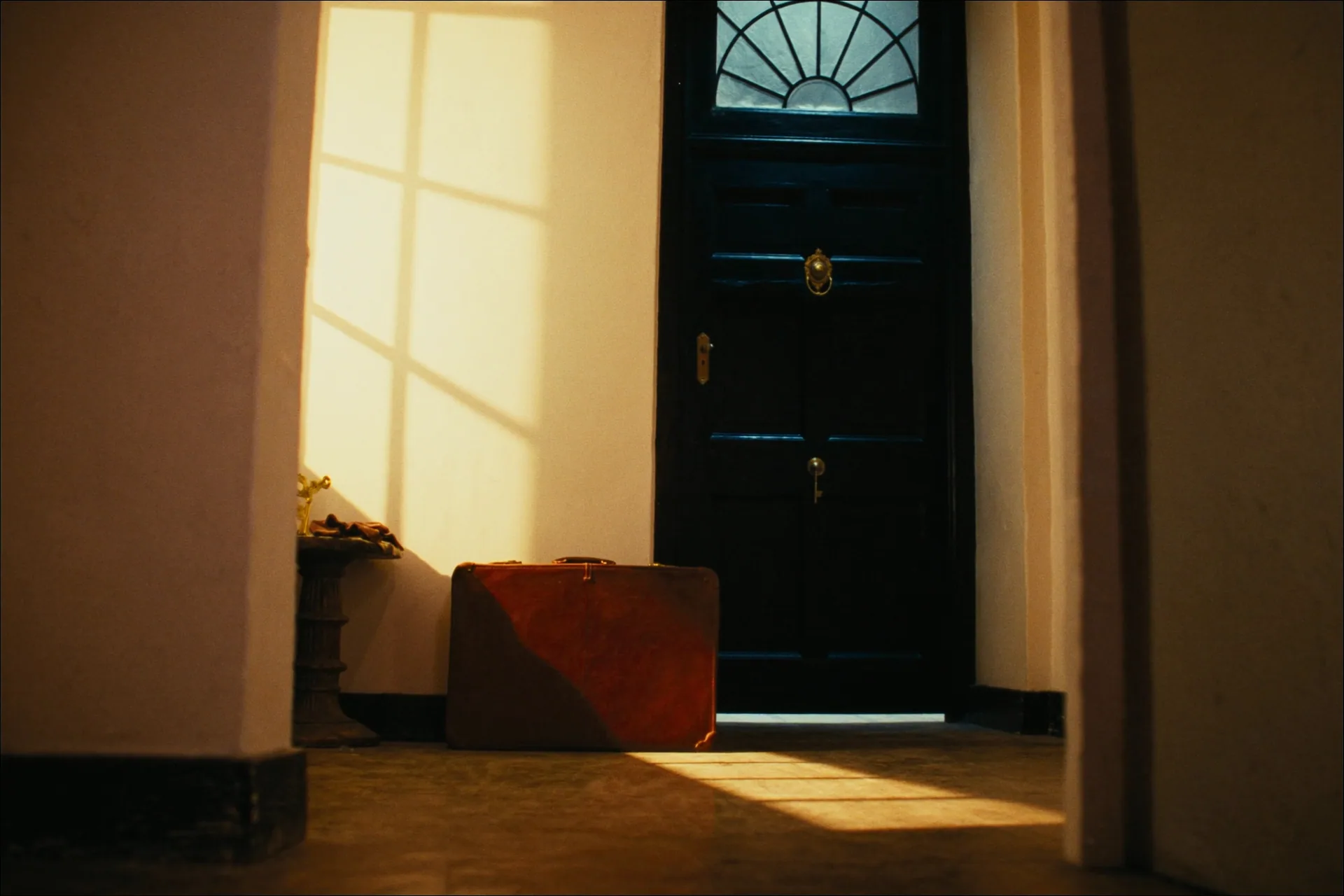 A leather suitcase by a polished front door, suggesting the journey of a UK property sale managed from overseas